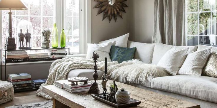 A pale sofa beside windows with light pillows, a blue accent pillow, and layered throws.