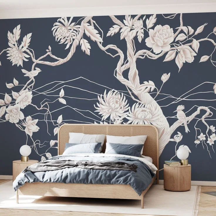 A navy floral accent wall frames a bed with blue bedding and matching round bedside tables.