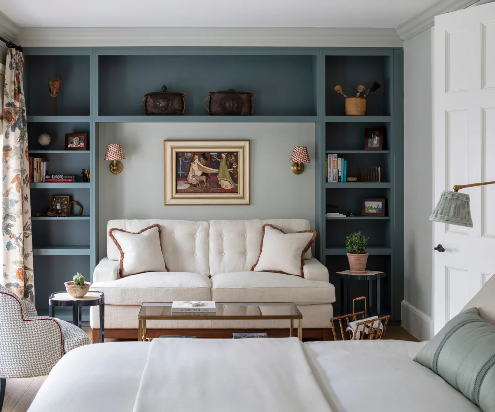 A floor lamp stands beside the seating area in a large bedroom suite.