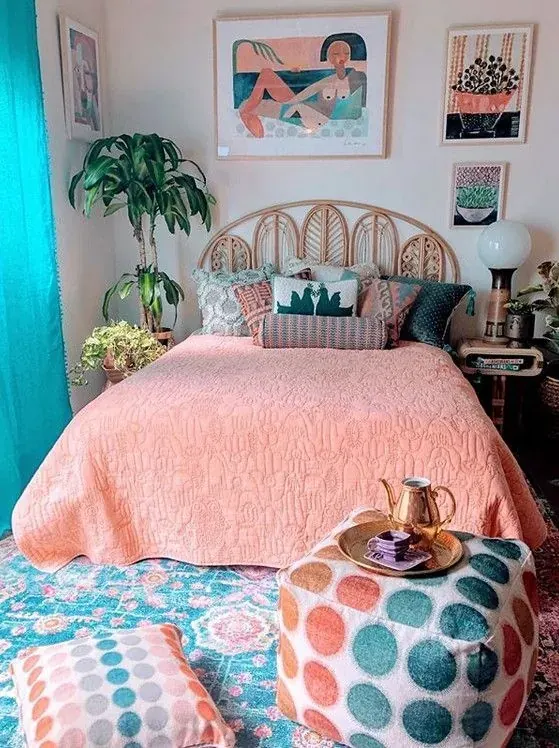 A pink bedcover sits beneath an arched woven headboard beside plants and a turquoise curtain.