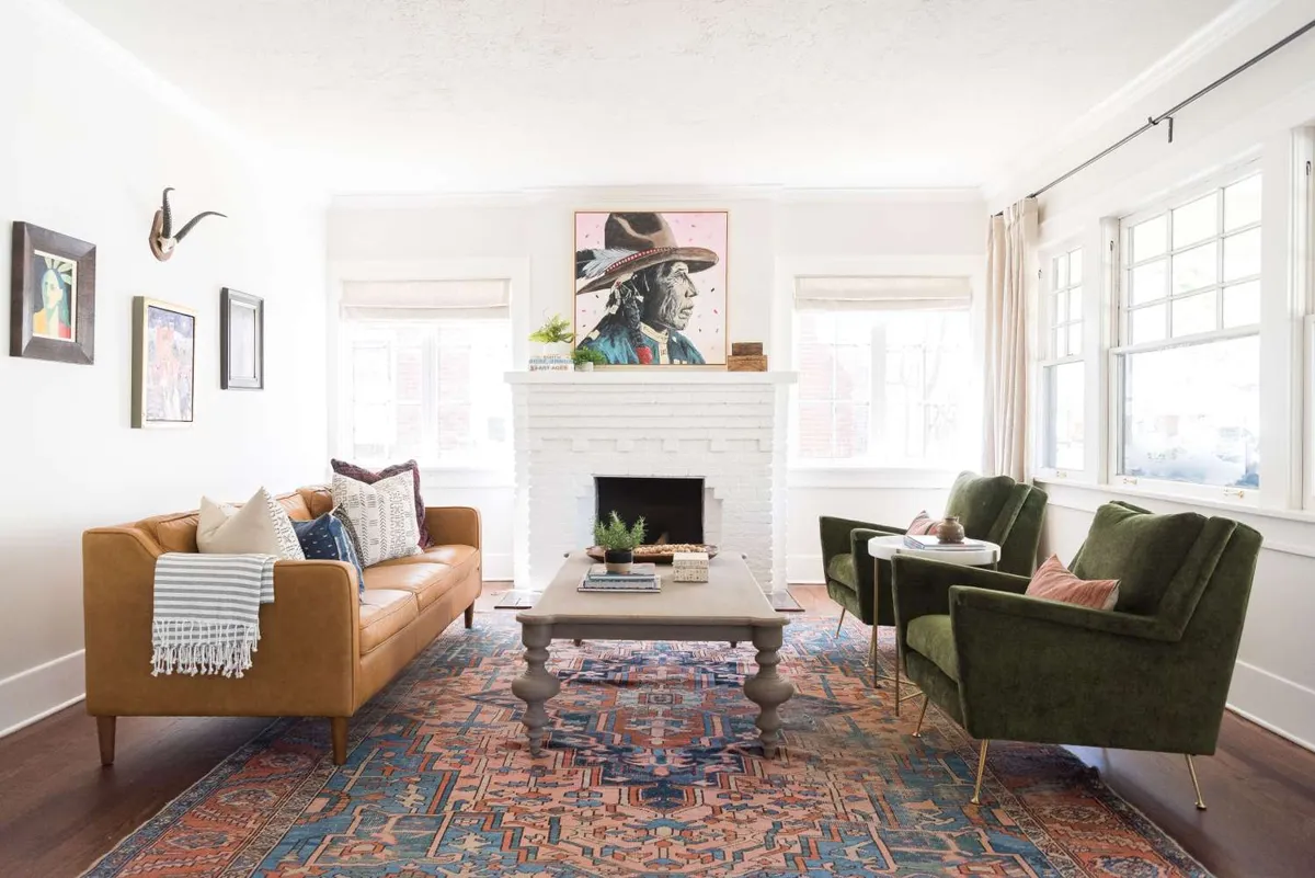 Brown sofa and green armchairs arranged around a multicolored rug