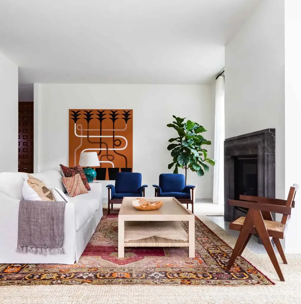 Colorful patterned rug layered over a larger pale rug around white seating