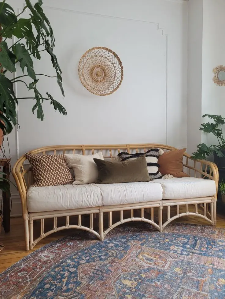 Woven-frame sofa with white cushions, brown pillows and a blue patterned rug