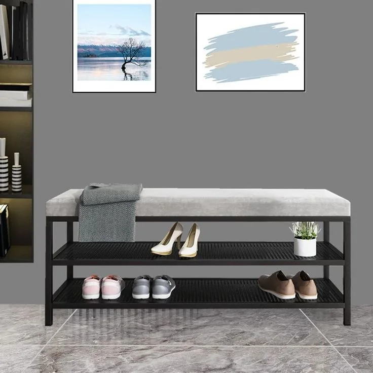 A gray upholstered bench has two open shelves holding shoes beneath the seat.