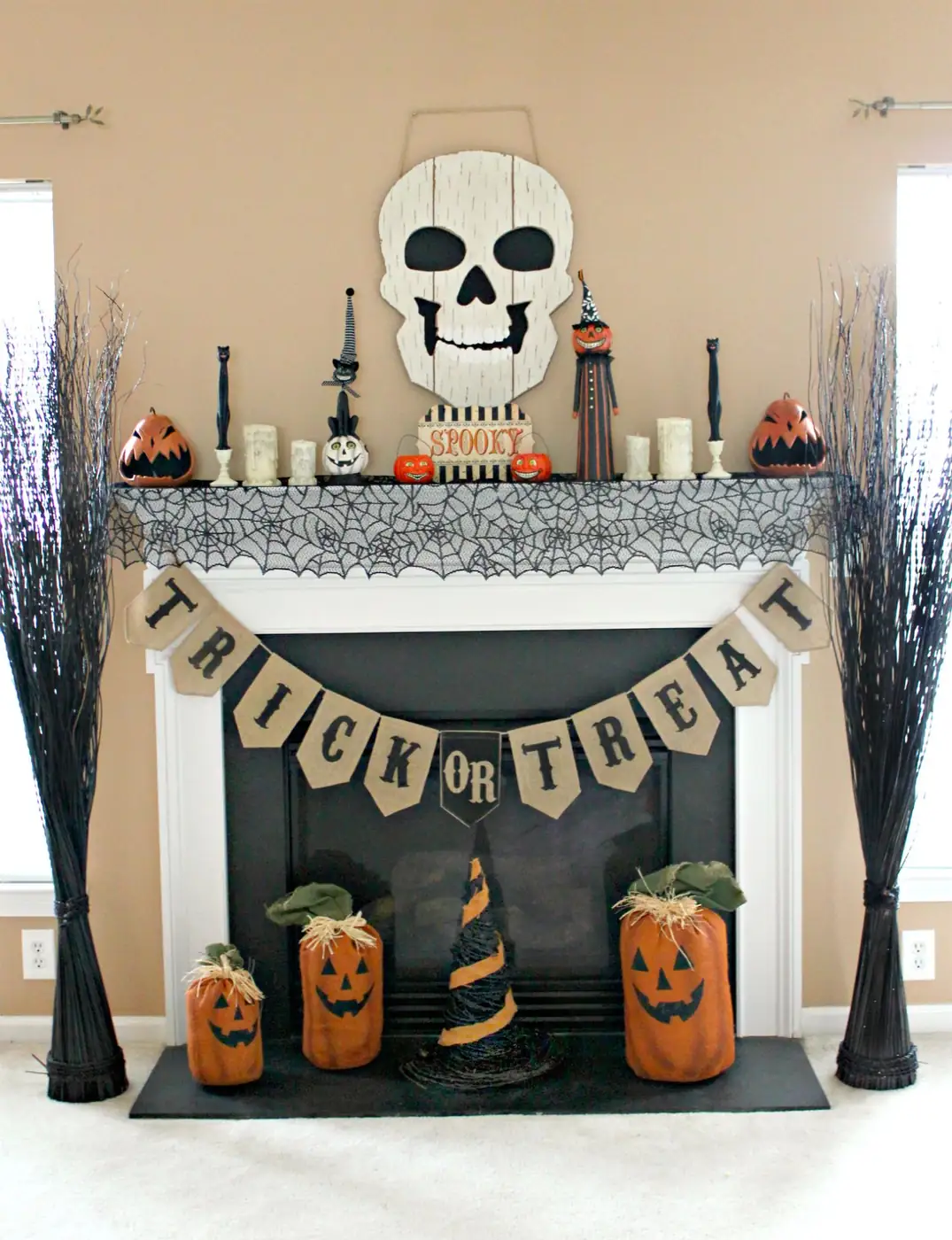 Large pale skull above a white mantel with orange pumpkin ornaments, black web-patterned fabric and a Trick or Treat banner