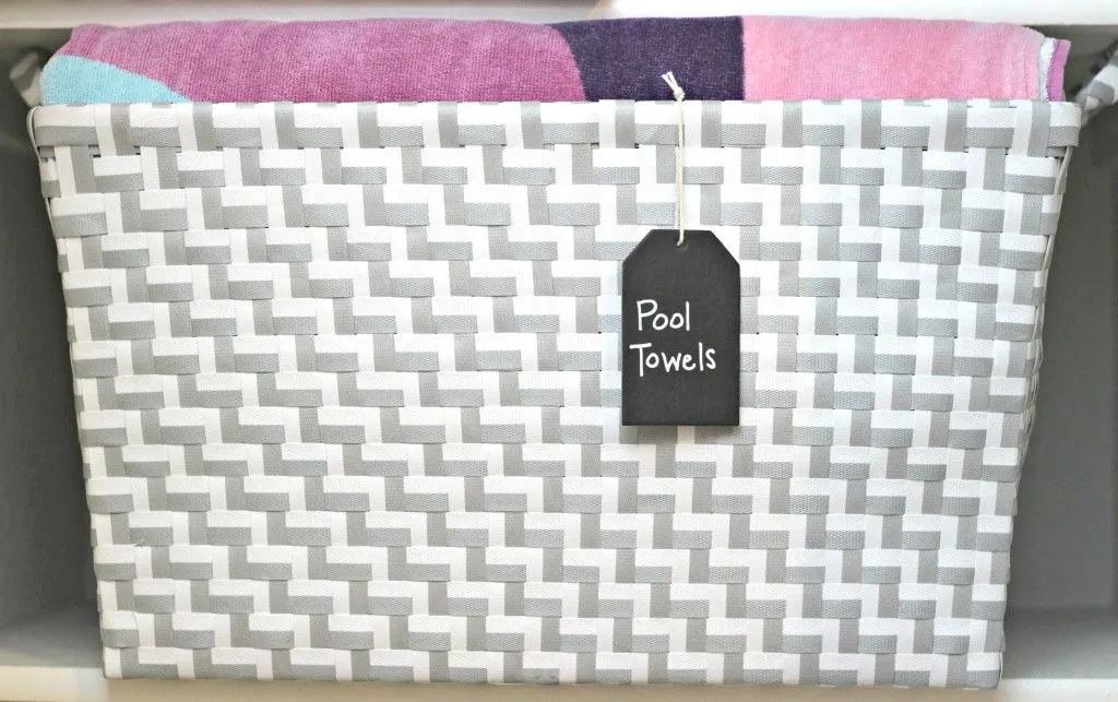 Colorful towels in a gray-and-white woven basket with a Pool Towels tag