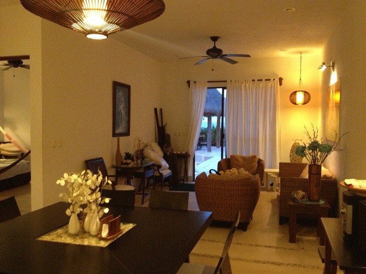 An evening living and dining space with glowing pendant lights and woven seating.