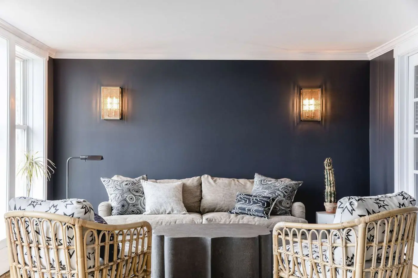 Two illuminated wall sconces above a gray sofa against a dark wall.