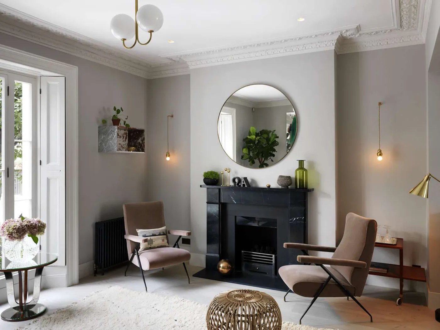 Two hanging bulbs flank a fireplace, with a brass-colored task lamp beside a chair.