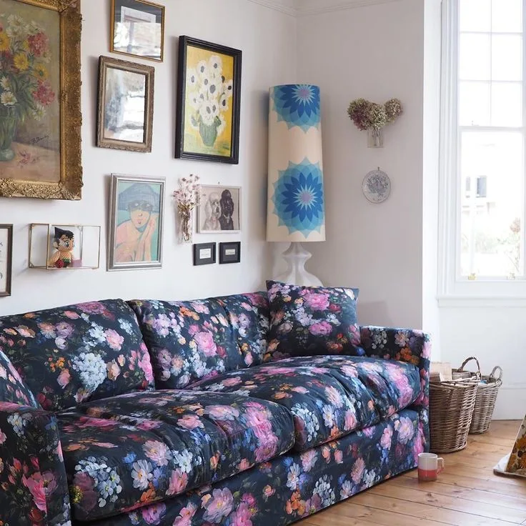 A mixed gallery of framed art hangs above a dark floral sofa.