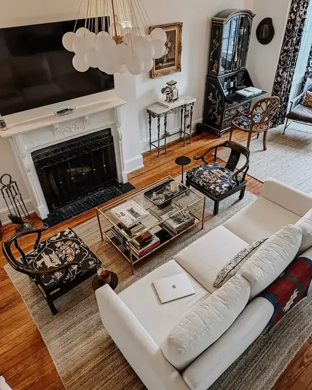 A white sofa faces a fireplace across a glass coffee table in a narrow living room.