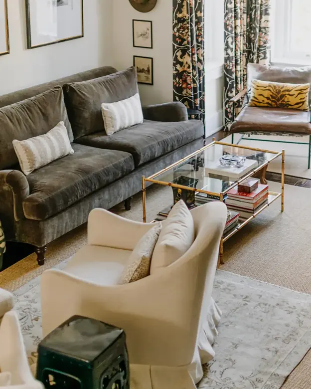 A gray sofa sits along a wall with a glass coffee table and an armchair opposite.