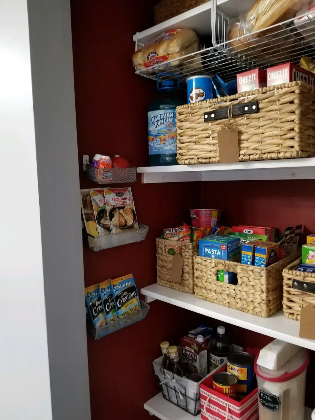 Woven pantry baskets hold boxed foods on white shelves, with smaller packets in shallow baskets on the left.