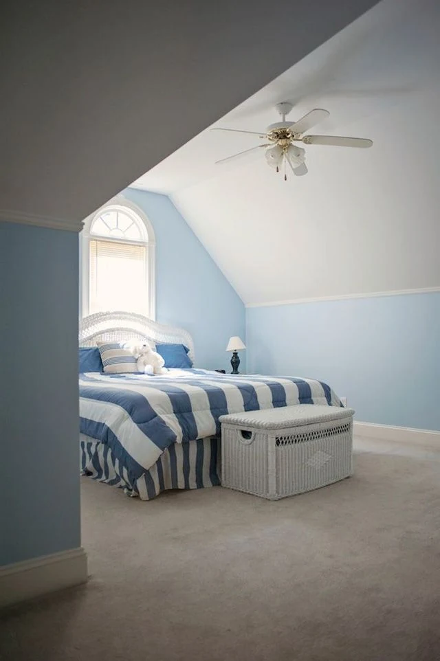 Blue-and-white bedding with a white chest at the foot of the bed.