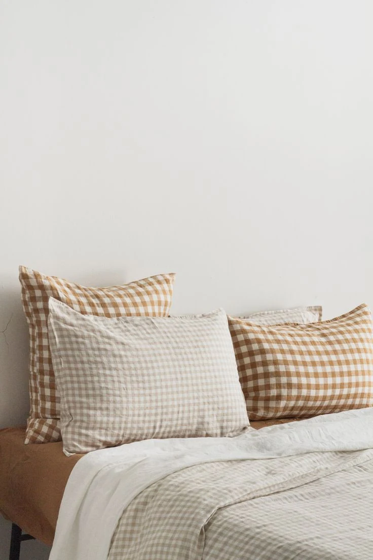 Gingham pillows and a pale checked throw against a plain bedroom wall.