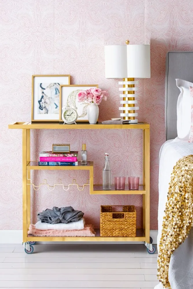 A wheeled bedside cart stores folded clothes, books and a small basket.