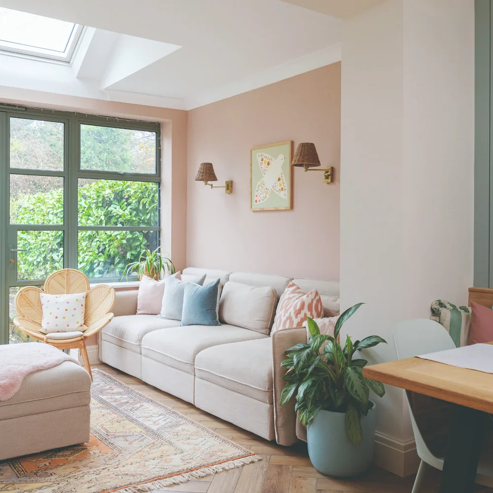 A pale sofa sits against a side wall beside large glazed doors, with a chair and ottoman nearby.