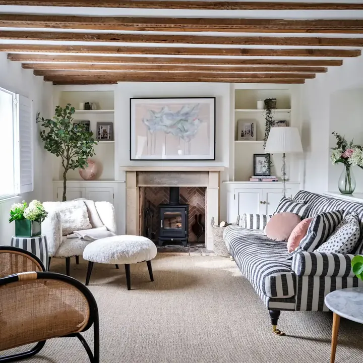 A striped sofa faces a pale chair and footstool beside a fireplace and shelves.